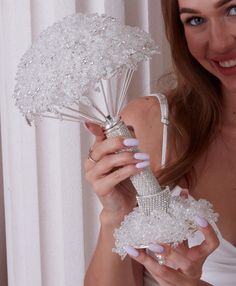 a woman in white dress holding an umbrella made out of pearls and diamonds on it