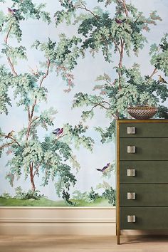 a dresser with drawers in front of a wallpapered tree and bird pattern on it