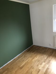 an empty room with hard wood floors and green painted walls, in the corner is a radiator