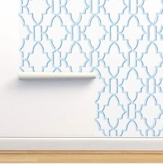 a white wall with a blue pattern on it next to a shelf and wooden floor