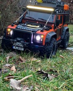 an orange and black toy truck with lights on it's hood in the grass