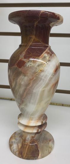 a marbled vase sitting on top of a white table next to a metal fence