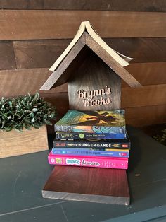 a stack of books sitting on top of a table next to a house shaped book holder