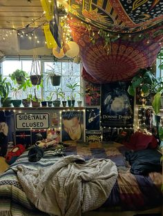 a bedroom with lots of plants hanging from the ceiling and posters on the wall above it