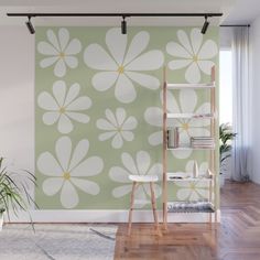 a green and white flower wall mural in a living room with wooden floors, potted plants and bookshelves