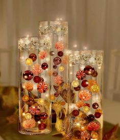 two vases filled with different colored glass beads and flowers on top of a table