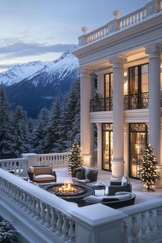 a large white house surrounded by trees and snow covered mountains in the background at night