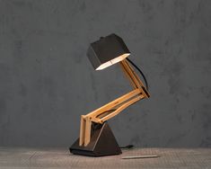 a desk lamp sitting on top of a wooden table next to a gray concrete wall