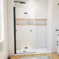 a bathroom with a glass shower door and wood flooring, along with a rug on the floor