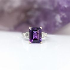 This Deep Purple Amethyst Ring is an elegant and timeless accessory crafted in solid 14k white gold. The emerald cut 10x8mm center stone is highlighted by sparkling baguette diamond accents. Perfect for February birthdays or to make a statement. Designer Silver Jewellery, Purple Amethyst Ring, Art Ring, February Birthday, Jewelry Showcases, Jewelry Safe, Timeless Accessories, Earring Findings, Pendant Bracelet