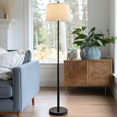 a living room with a blue couch and a lamp on the floor next to a window