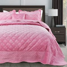 a pink comforter set on a bed in a bedroom