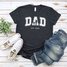 a t - shirt with the word dad on it next to some jeans and shoes