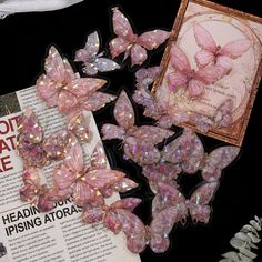 some pink butterflies are sitting on top of a book and next to it is a framed picture