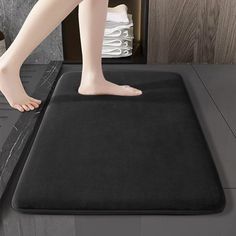 a person standing on top of a black mat in a bathroom next to a sink