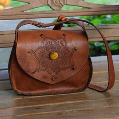 Thick full-grain leather in a warm brown hue becomes a unique shoulder bag in the hands of Brazil's Vera Mariano. The bag is crafted by hand and decorated with a mandala motif using pyrography techniques. Centering the mandala and accenting its edges are stones of natural tiger's eye. The unlined bag features a long adjustable strap an interior zipper pocket and a magnetic snap closure. Leather Bags Handmade Women, Pyrography Techniques, Eye Mandala, Imperial Leather, Tooling Patterns, Bags Handmade, Brown Shoulder Bag, Vintage Purse, Leather Projects