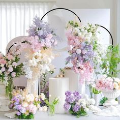 there are many flowers in vases on the table and behind them is a mirror