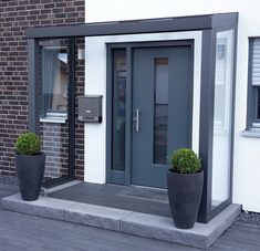 two large black planters are in front of the door to a building with brick walls