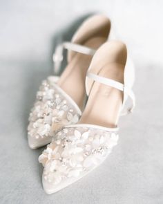 a pair of white shoes with pearls on the toes and heels are sitting on a gray surface