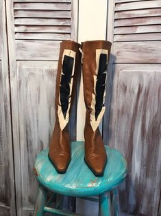 a pair of brown and white boots sitting on top of a blue stool next to wooden shutters