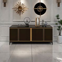 a living room with white walls and gold accents on the wall, along with an art deco style sideboard