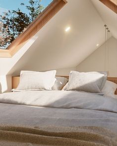 an attic bedroom with white linens and pillows