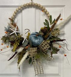 a wreath made out of branches, leaves and other things is hanging on the door