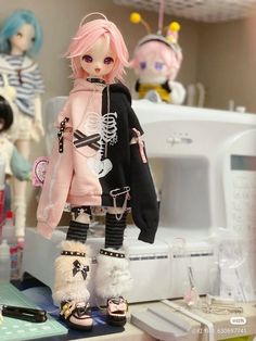 a doll with pink hair is standing on a table next to other dolls and sewing machines