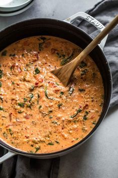 a large pot filled with red sauce and spinach on top of a gray table