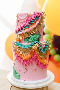 a pink and gold birthday cake on a table