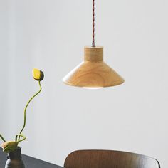 a wooden table with a vase on it and a light hanging from the ceiling