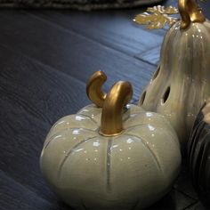 two ceramic pumpkins sitting next to each other on a wooden table with gold accents