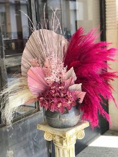 a vase filled with pink flowers and feathers