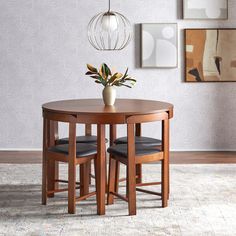 a wooden table with two chairs and a vase on top of it in a room