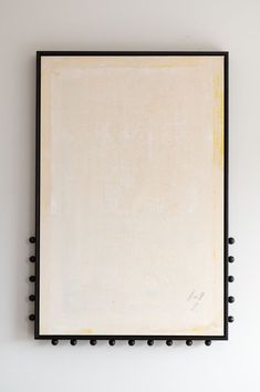 a black frame hanging on the wall above a white board with riveted edges