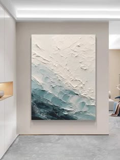 an abstract painting hangs on the wall in a modern living room with white walls and grey flooring