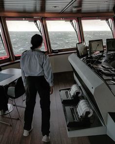 a woman standing in front of a window looking out at the ocean from inside a boat