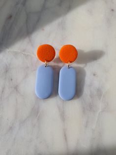 two blue and orange earrings sitting on top of a marble counter next to each other