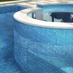 an empty swimming pool with blue tiled walls and water features in the center, surrounded by grass