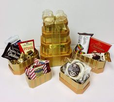 a group of gold boxes filled with assorted chocolates and candies on top of each other