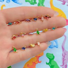 Let's go back in time in the Dino-Mite Stud Set! We love how fun these dinosaur studs are and they'll definitely add so much personality to any outfit! 18k gold plated, 18k rose gold plated, or rhodium plated over brass Cubic zirconia stones Approx. 4mm wide Sterling silver posts and butterfly backings Four mismatched Dinosaur Dance, Beautiful Trinkets, Dinosaur Stuff, Ear Stacks, Trinkets Jewelry, Character Customization, Ear Curation, Paintings Tutorials, Dinosaur Necklace