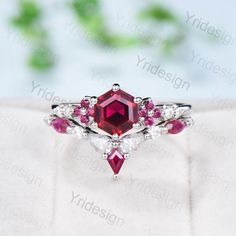 an engagement ring with a red stone surrounded by white diamonds and rubish stones on top