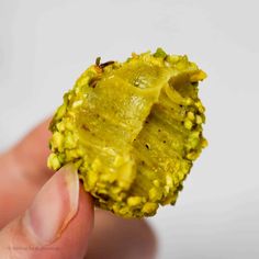 a hand holding a piece of broccoli with yellow florets on it