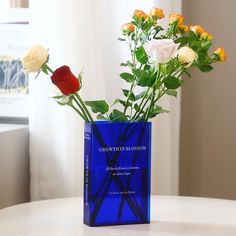 two roses in a blue vase on a table