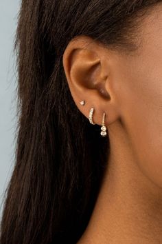 a close up of a woman's ear with two small diamond earrings on it