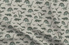 a white fabric with green dinosaurs on it