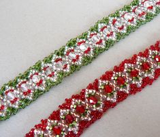 two red and green beaded bracelets sitting on top of a white table next to each other