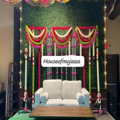 a couch sitting under a green wall covered in flowers and greenery next to a coffee table