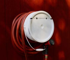 a red hose connected to a white water tank on the side of a wooden wall