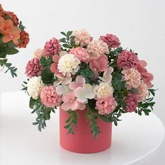 two vases filled with flowers sitting on top of a white table next to each other